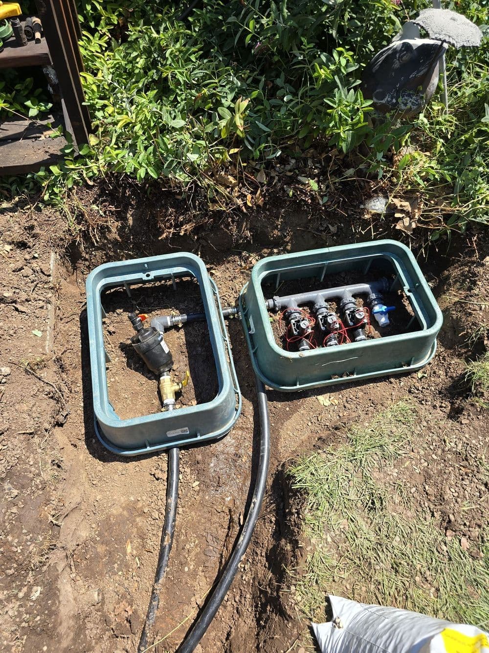 Irrigation system valves and control box installed outdoors in a garden.