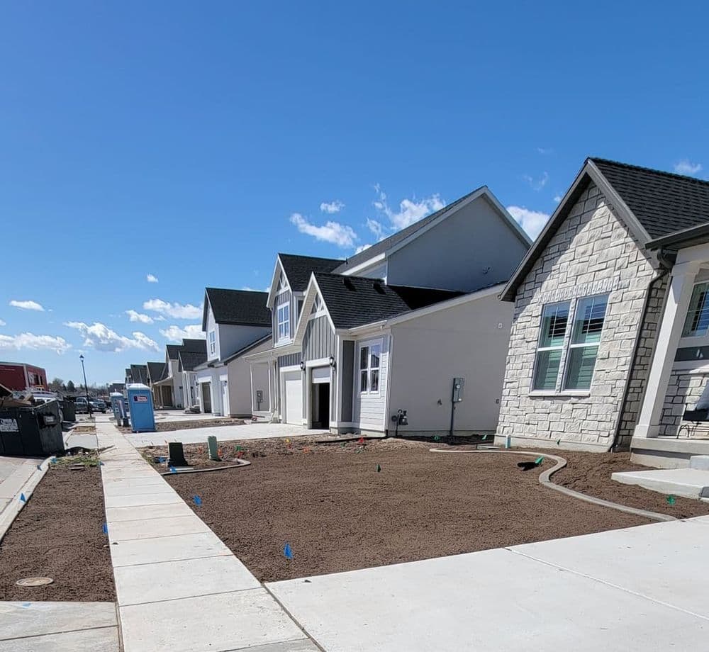 New residential homes under construction with freshly landscaped yards and clear blue sky.